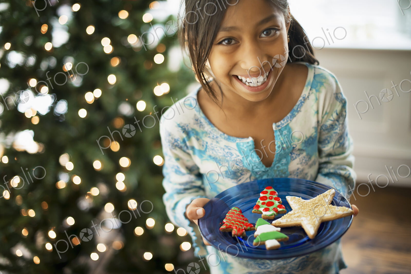 A young girl holding a plate of organic decorated Christmas cookies