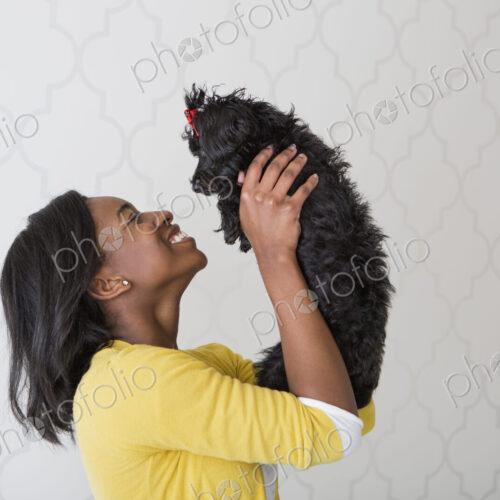 A young girl holding her small black pet dog. A young girl holding her small black pet dog.