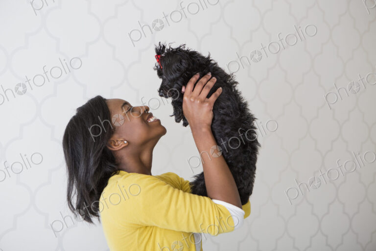 A young girl holding her small black pet dog.