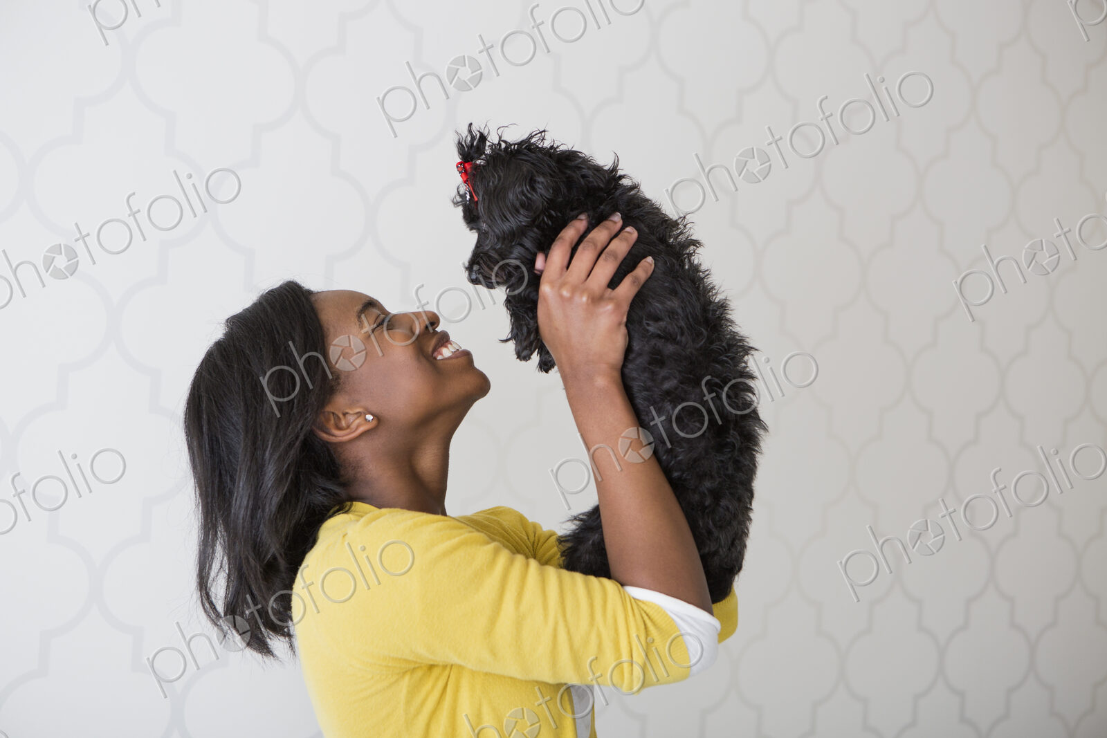 A young girl holding her small black pet dog.