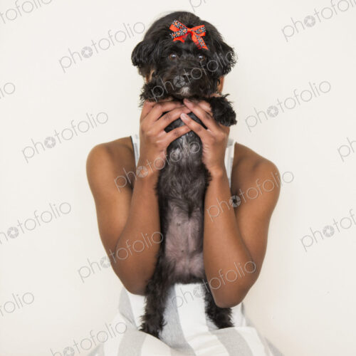 A young girl holding her small black pet dog.