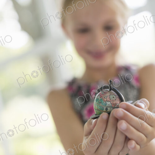 A young girl holding out a small globe in the palms of her cupped hands. A young girl holding out a small globe in the palms of her cupped hands.