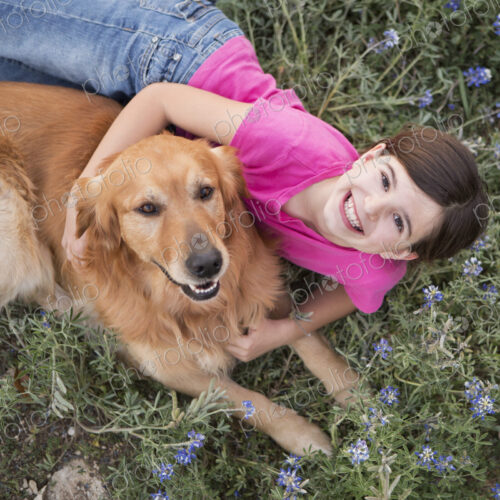 A young girl hugging a golden retriever pet.