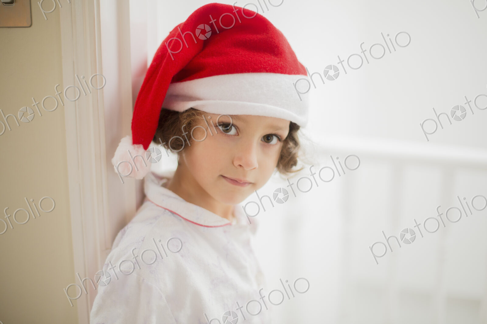 A young girl in a Santa hat on Christmas morning.