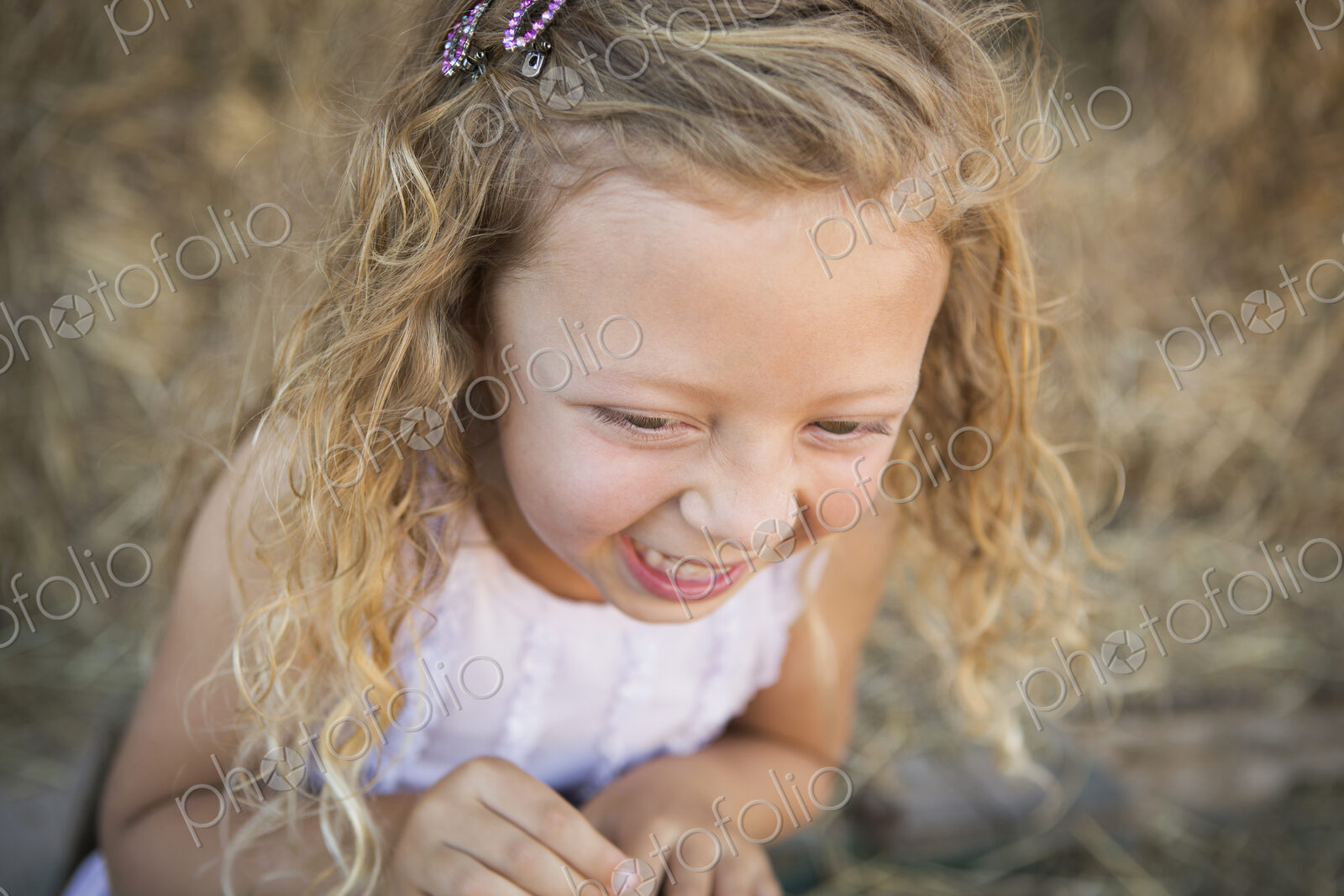 A young girl in a barn laughing.