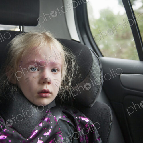 A young girl in a car seat in Halloween costume.