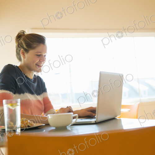 A young girl in a coffee shop using a laptop computer.