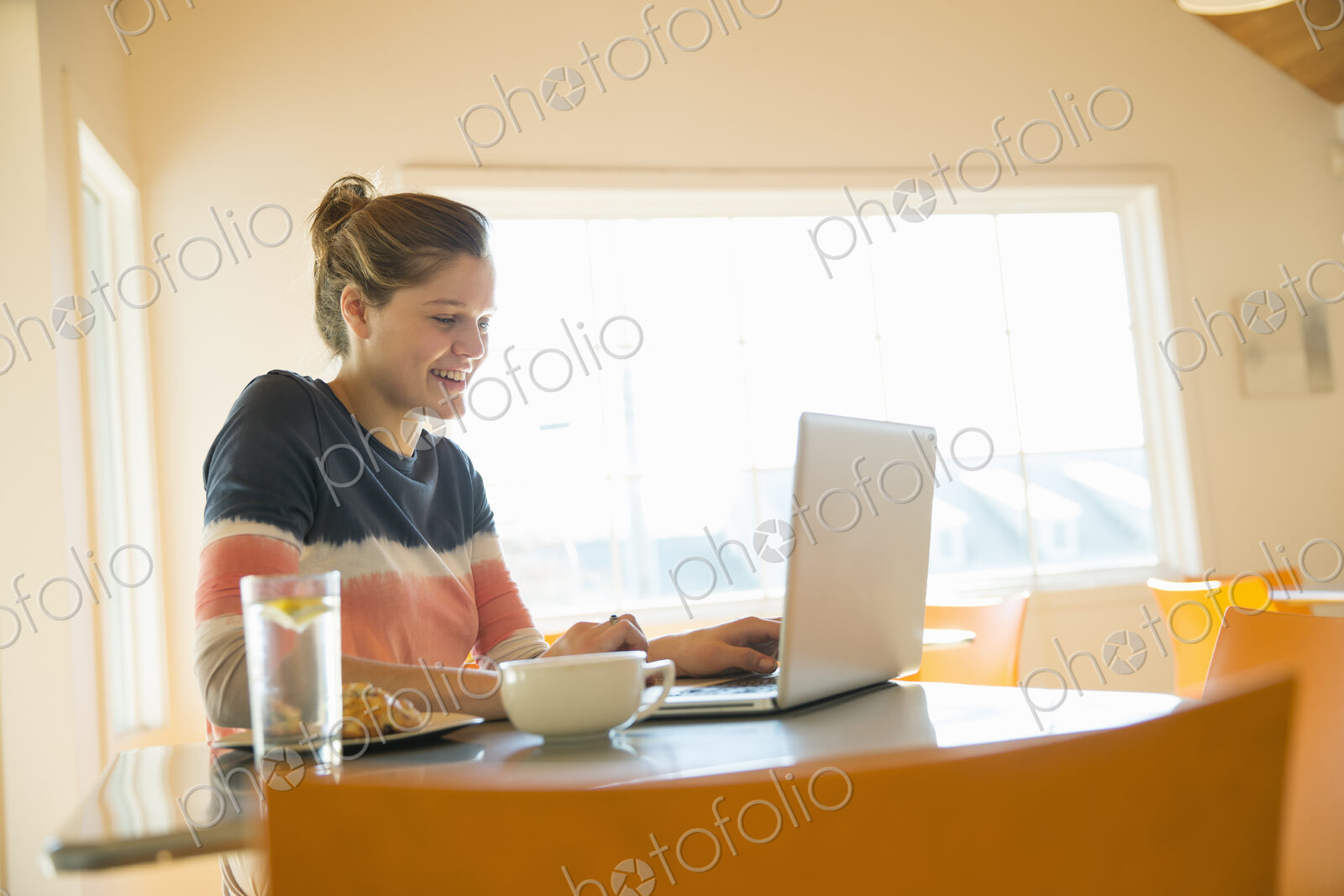 A young girl in a coffee shop using a laptop computer.