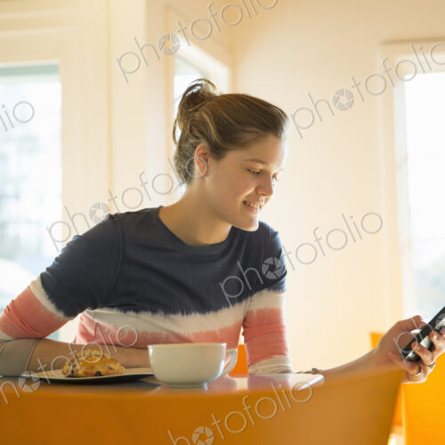 A young girl in a coffee shop.Using her cell phone. A young girl in a coffee shop.Using her cell phone.