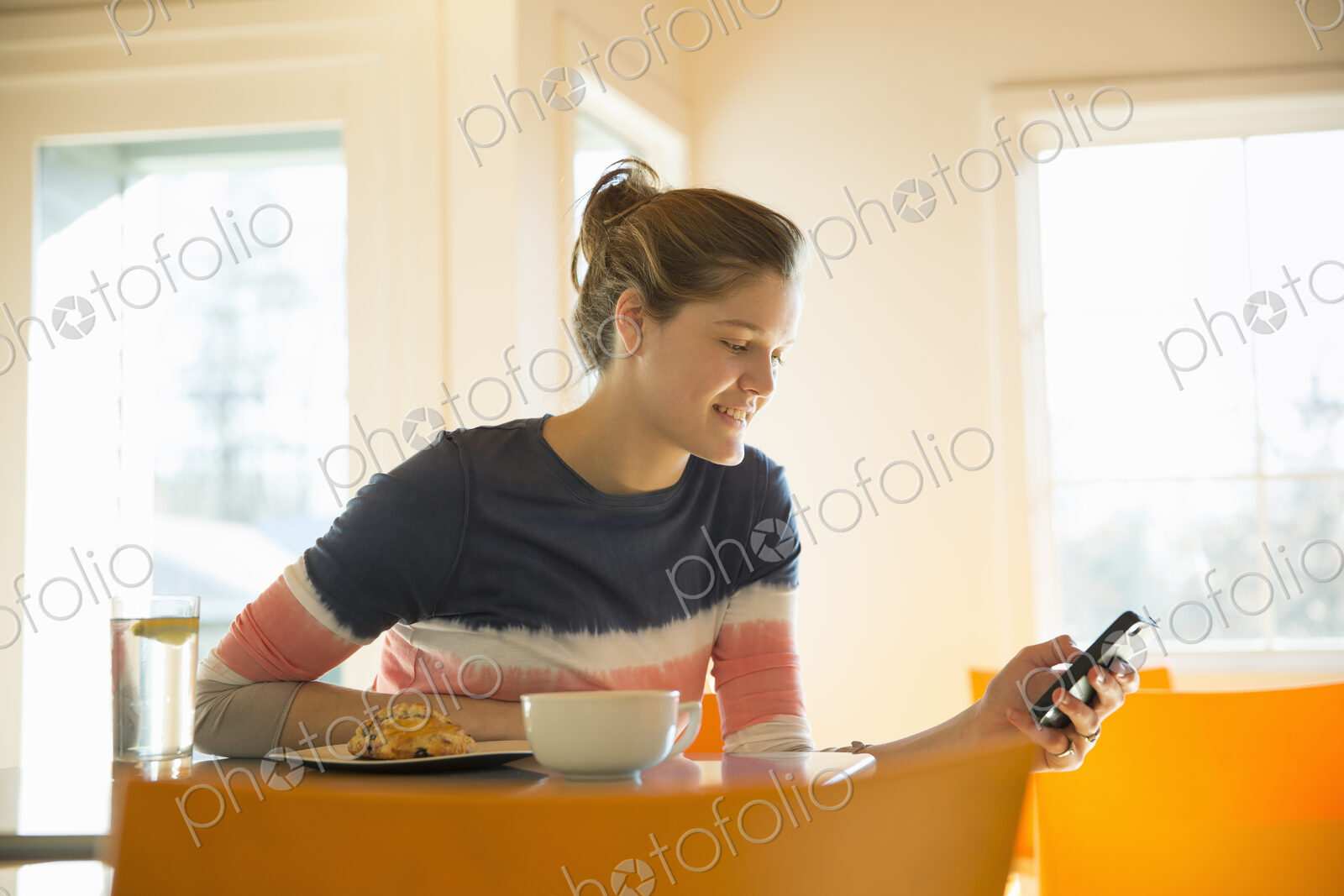 A young girl in a coffee shop.Using her cell phone.