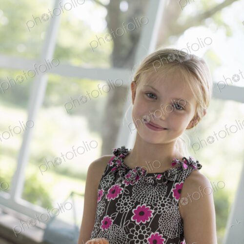 A young girl in a floral dress holding a peach fruit. A young girl in a floral dress holding a peach fruit.