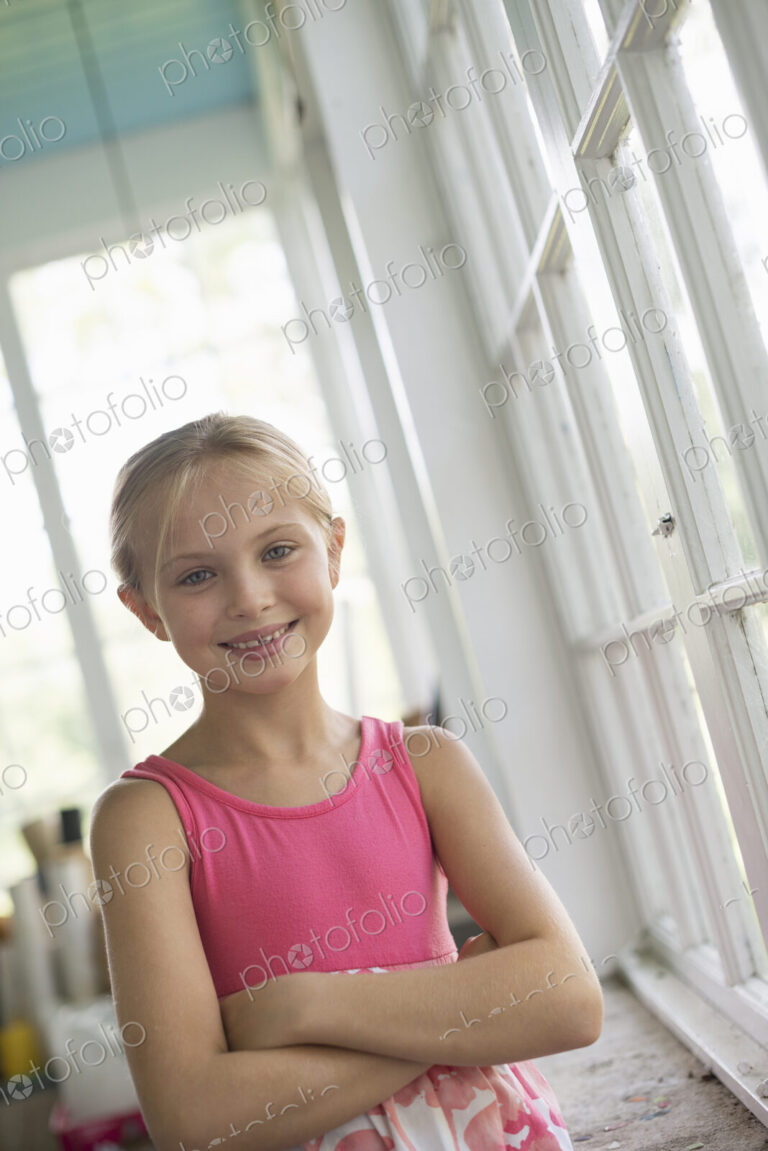 A young girl in a kitchen wearing a pink dress.