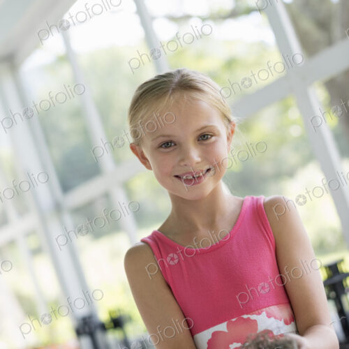 A young girl in a kitchen wearing a pink dress. Holding a bird;s nest. A young girl in a kitchen wearing a pink dress. Holding a bird;s nest.
