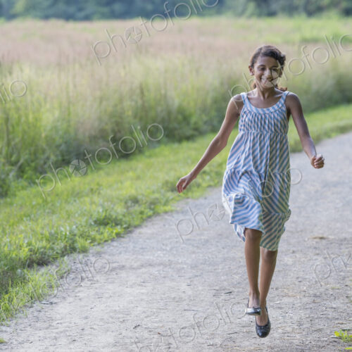 A young girl in a summer dress walking along a path. A young girl in a summer dress walking along a path.