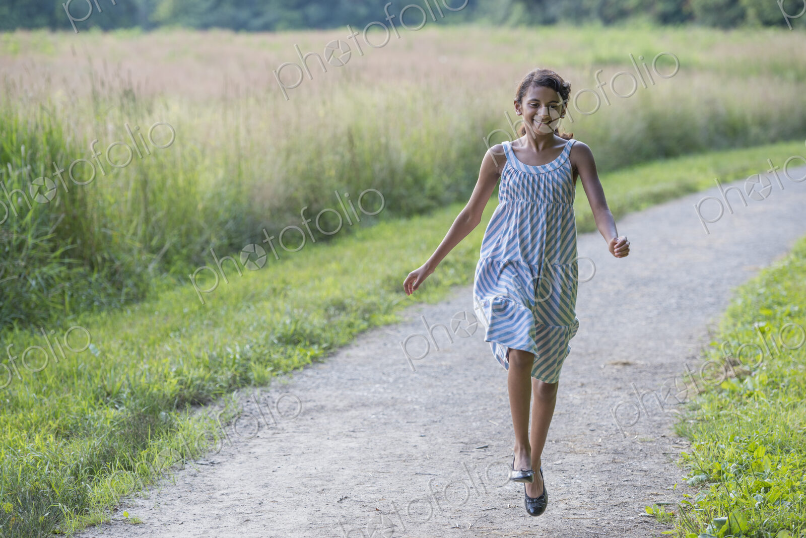 A young girl in a summer dress walking along a path.