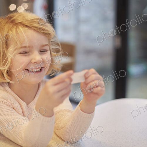 A young girl laughing and looking at a small piece of paper, a joke from a Christmas… A young girl laughing and looking at a small piece of paper, a joke from a Christmas…