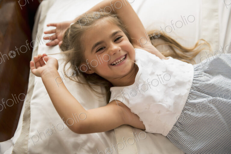 A young girl looking at the camera, smiling.