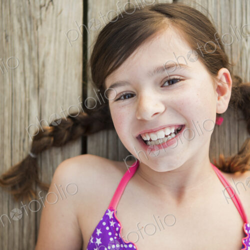 A young girl lying on a jetty looking upwards.