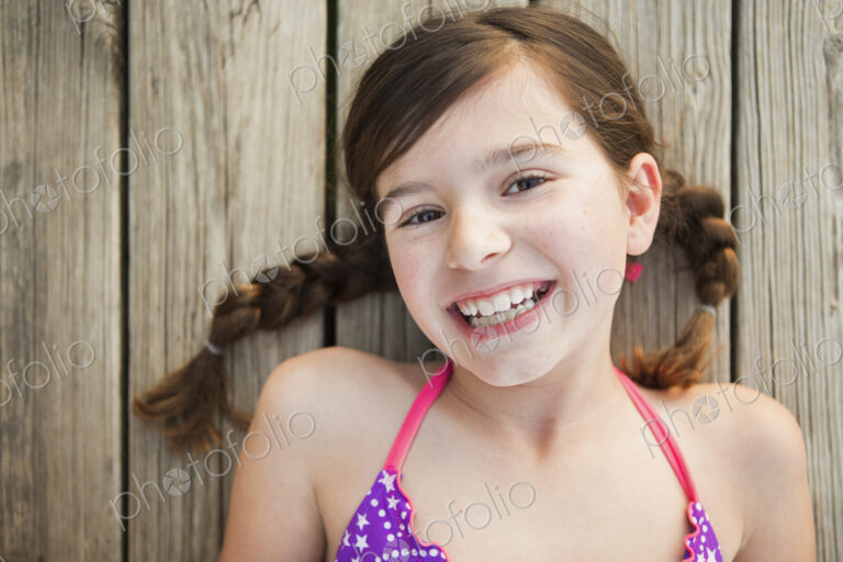 A young girl lying on a jetty looking upwards.