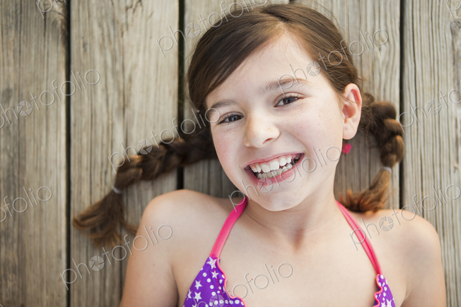 A young girl lying on a jetty looking upwards.