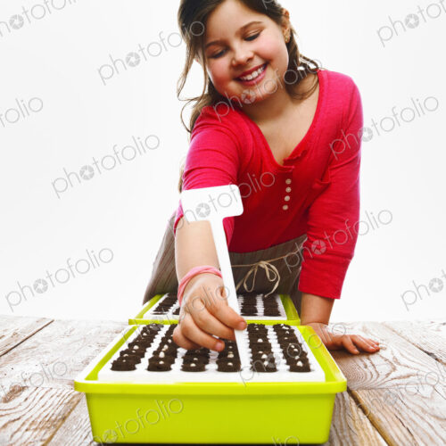 A young girl planting seeds in a modular seed tray with dark organic soil. A young girl planting seeds in a modular seed tray with dark organic soil.
