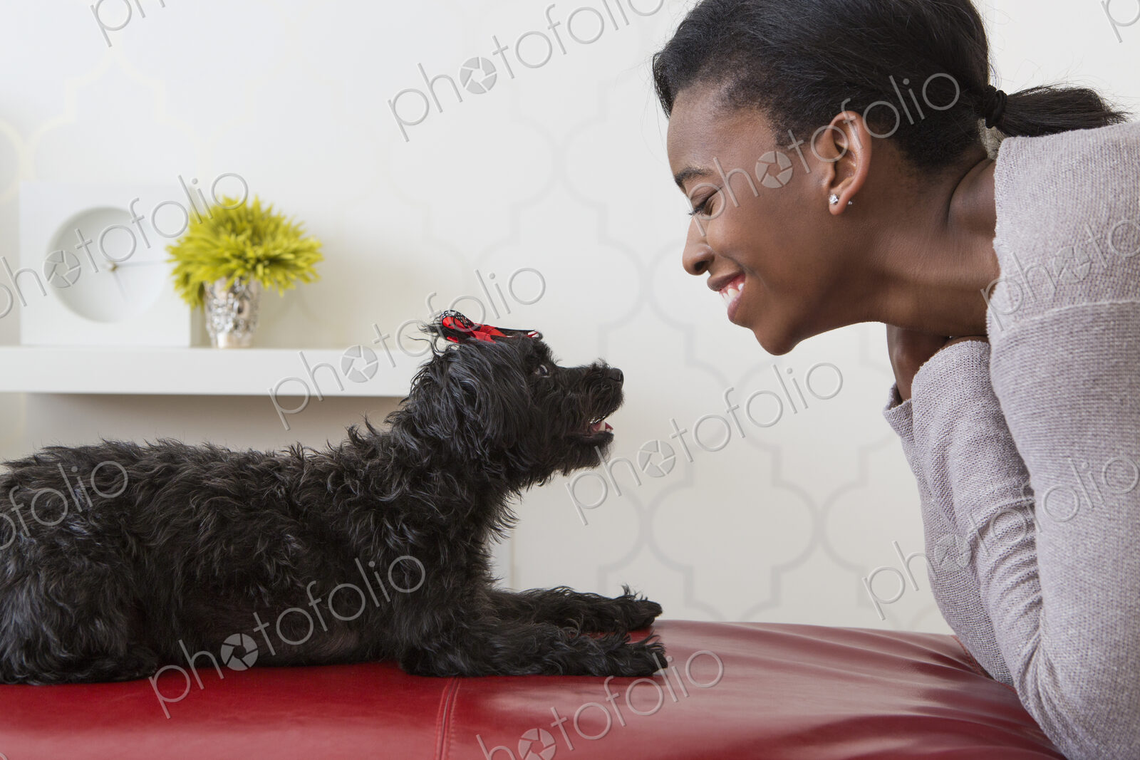 A young girl playing with her small black pet dog.