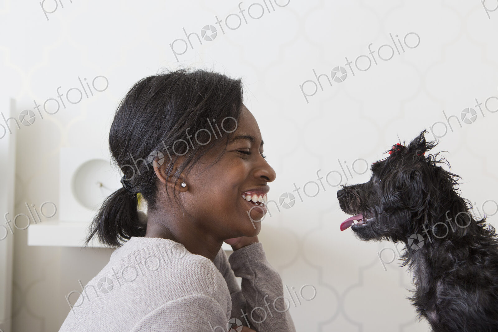 A young girl playing with her small black pet dog.