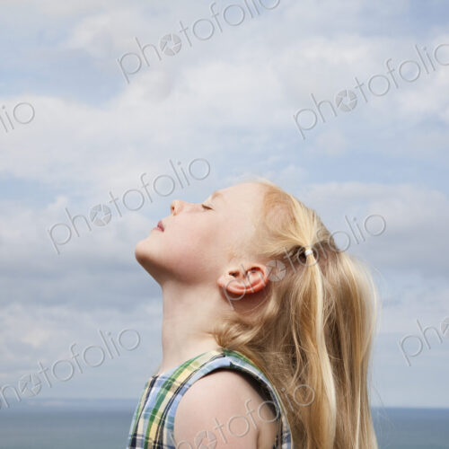 A young girl raising her face to the sun. A young girl raising her face to the sun.