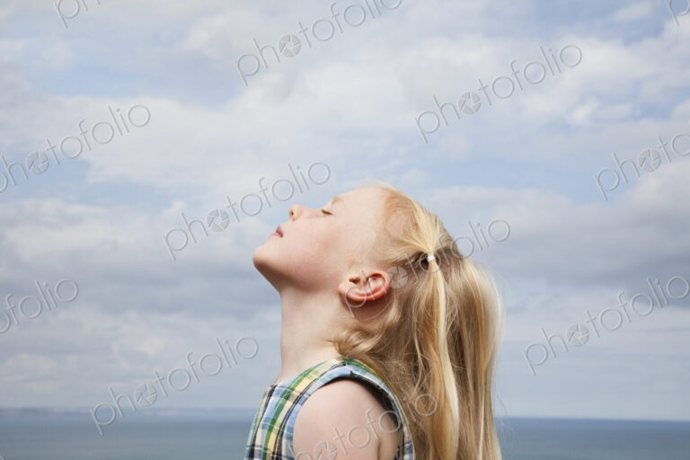 A young girl raising her face to the sun.