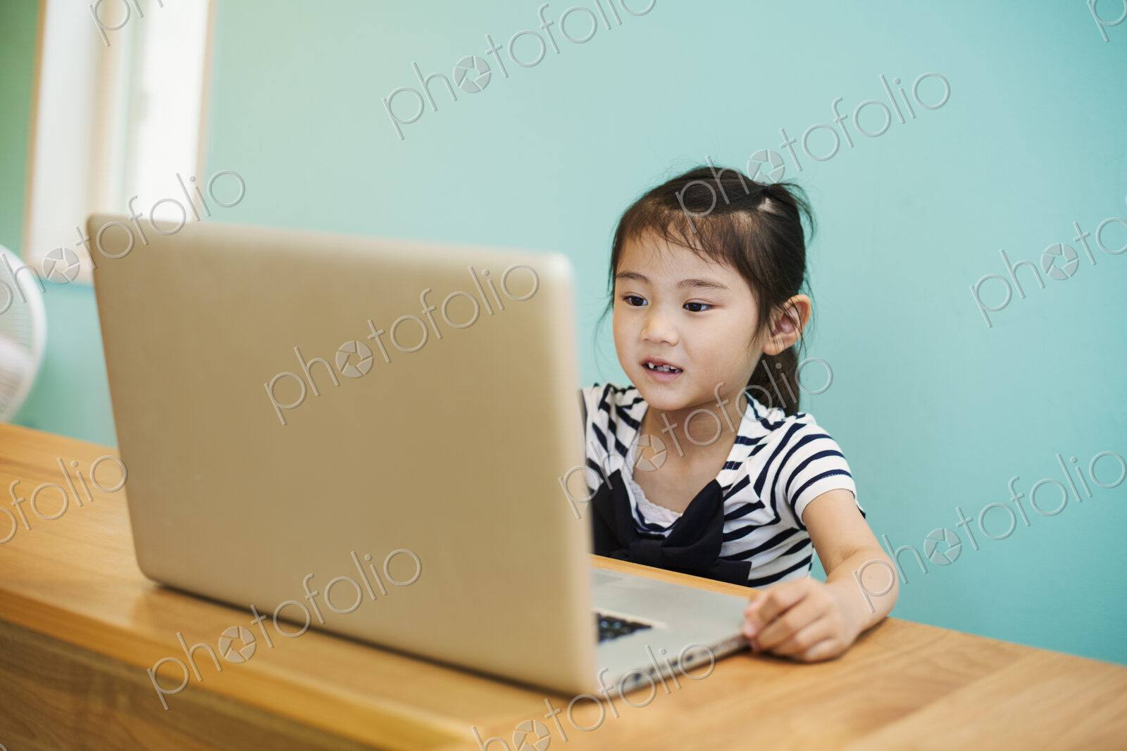A young girl seated at a laptop computer in a classroom.