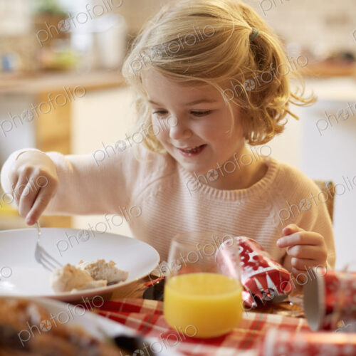 A young girl sitting at a table having a meal. A young girl sitting at a table having a meal.