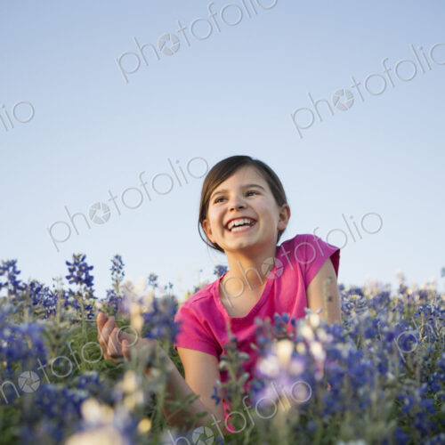A young girl sitting in a field of wild flowers, laughing. A young girl sitting in a field of wild flowers, laughing.