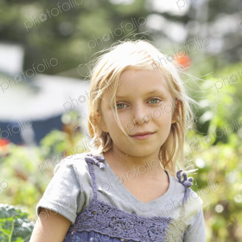A young girl sitting in among the fresh green foliage of a garden. Vegetables and… A young girl sitting in among the fresh green foliage of a garden. Vegetables and…