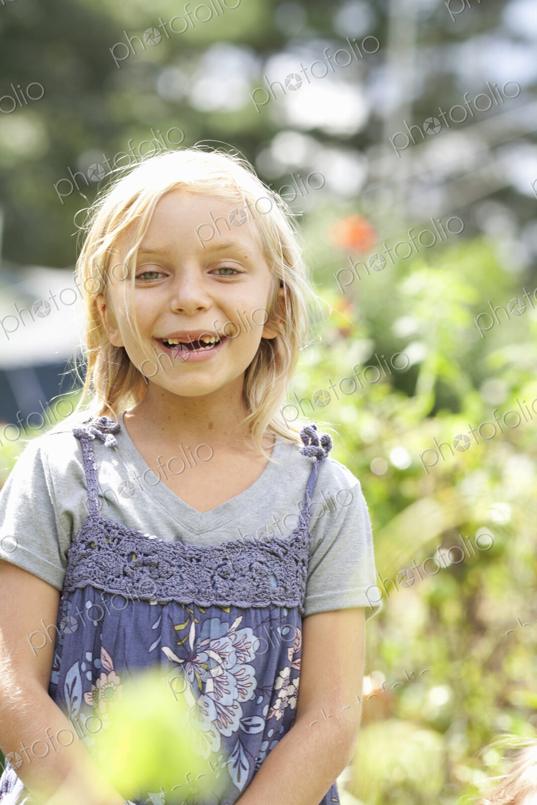 A young girl sitting in among the fresh green foliage of a garden. Vegetables and…
