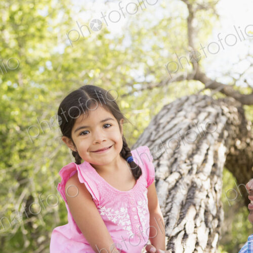 A young girl sitting on a tree trunk beside her father. A young girl sitting on a tree trunk beside her father.