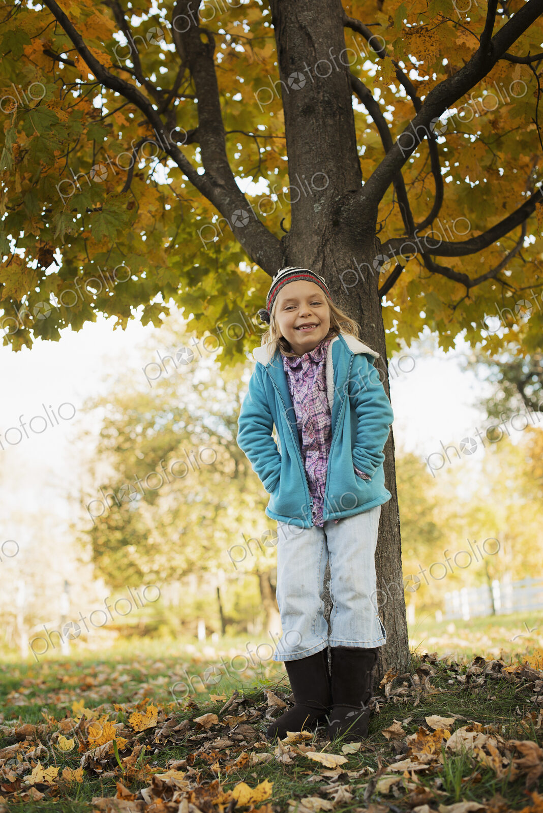 A young girl standing under a tree, on a farm. Autumn foliage.