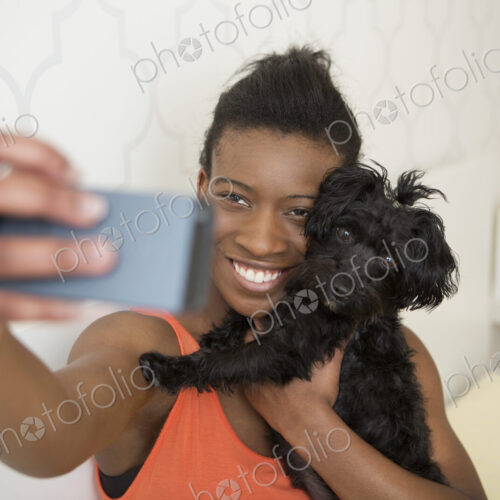 A young girl taking a selfy of her small pet dog and herself.