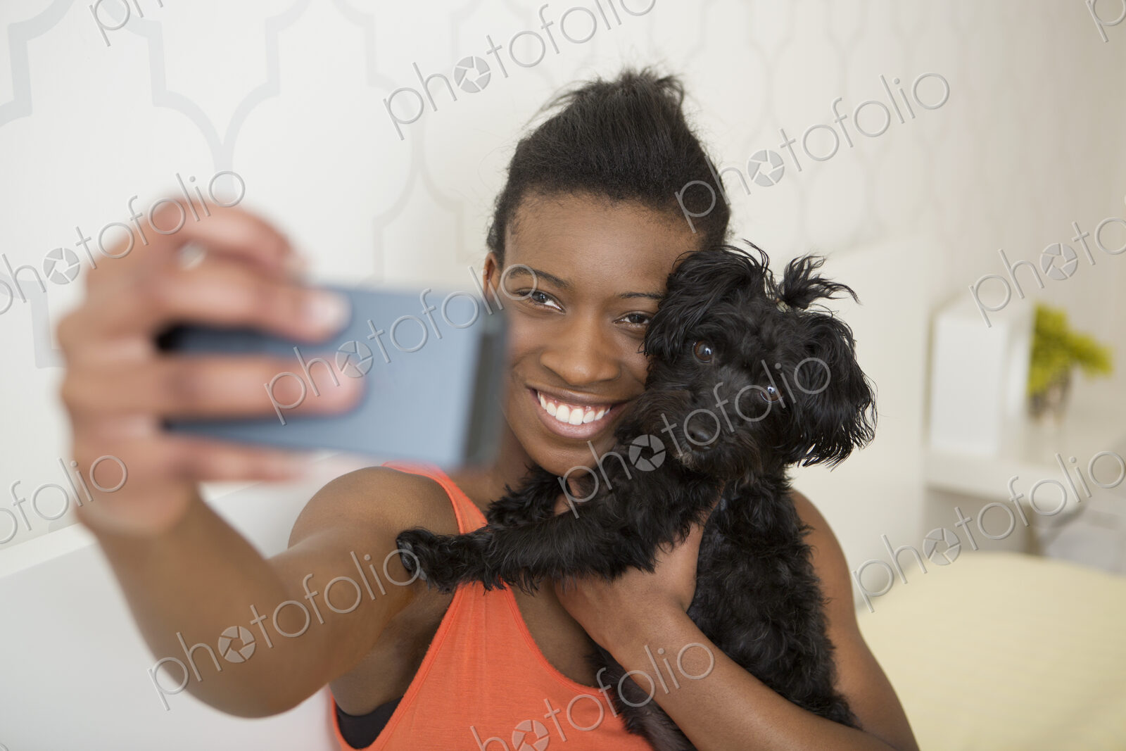 A young girl taking a selfy of her small pet dog and herself.