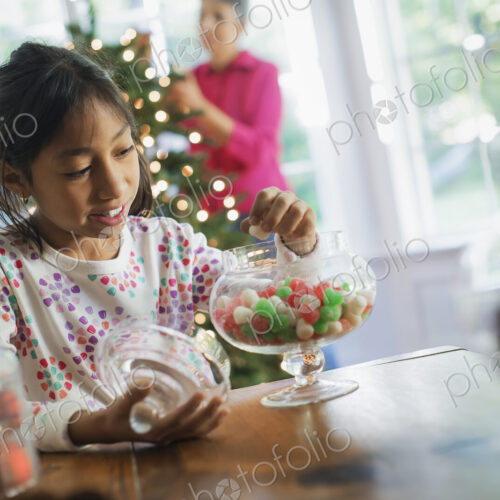 A young girl with a large glass jar of organic holiday gum drops. Decorations for…