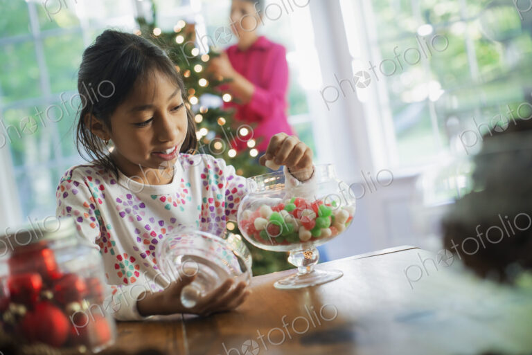 A young girl with a large glass jar of organic holiday gum drops. Decorations for…