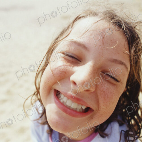 A young girl with a wide grin, eyes half closed, and wet hair outside in the rain. A young girl with a wide grin, eyes half closed, and wet hair outside in the rain.