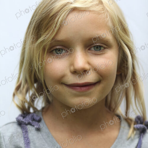 A young girl with blonde hair, and blue eyes. Smiling and looking at the camera. A young girl with blonde hair, and blue eyes. Smiling and looking at the camera.