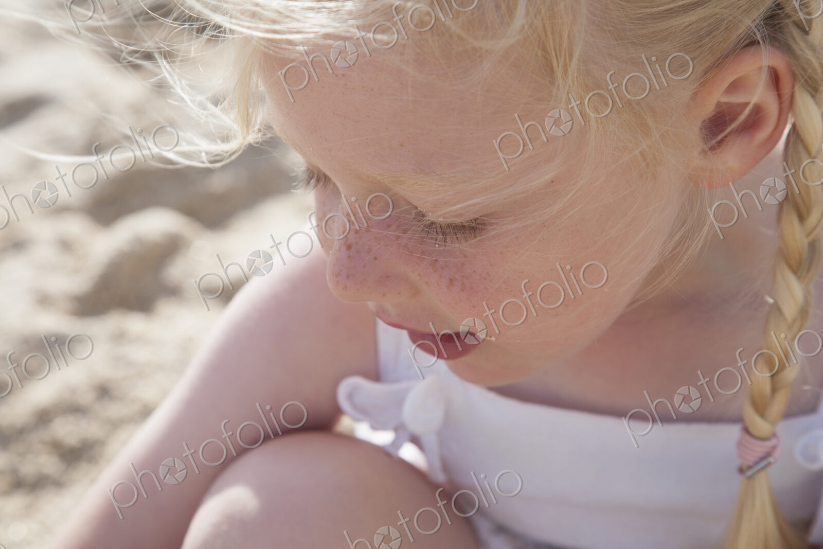 A young girl with blonde hair in pigtails on the beach.