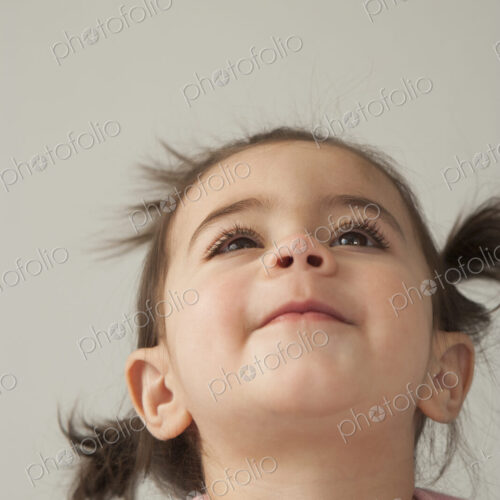A young girl with brown eyes and dark hair in bunches. Looking upwards with her head… A young girl with brown eyes and dark hair in bunches. Looking upwards with her head…
