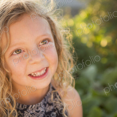 A young girl with long red curly hair outdoors in a garden. A young girl with long red curly hair outdoors in a garden.