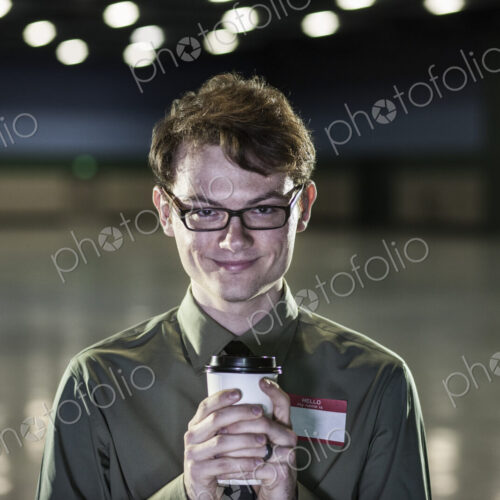 A young hip businessman standing in a dimly lit and dark exhibition area in a… A young hip businessman standing in a dimly lit and dark exhibition area in a…
