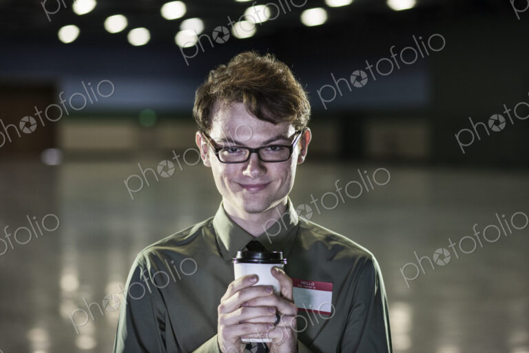 A young hip businessman standing in a dimly lit and dark exhibition area in a…