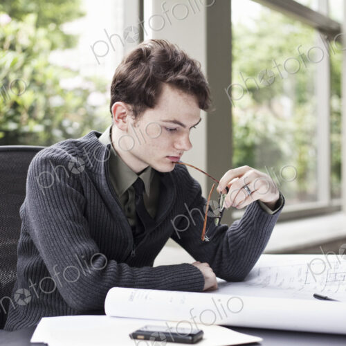 A young hip businessman working on architectural plans in his office. A young hip businessman working on architectural plans in his office.