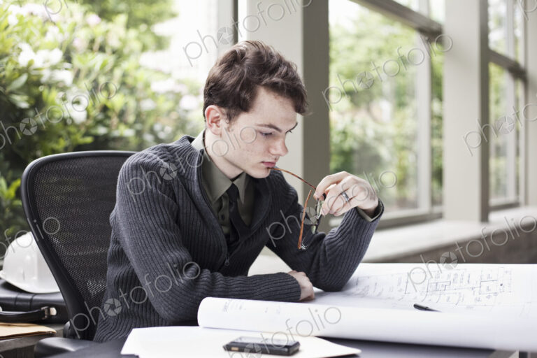 A young hip businessman working on architectural plans in his office.