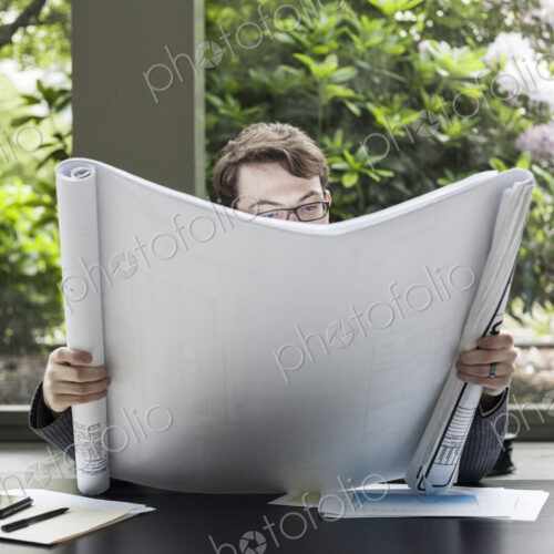 A young hip businessman working on architectural plans in his office. A young hip businessman working on architectural plans in his office.